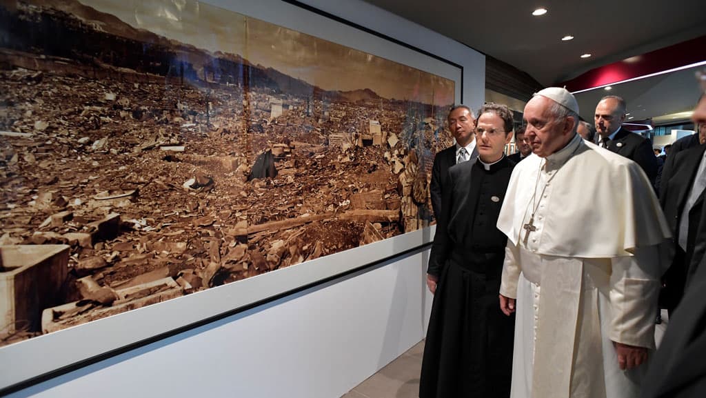 Pope Francis walks by a photo showing the destruction created by an atomic bomb during his Nov. 26, 2019, visit to the Jesuit-run Sophia University in Tokyo. (CNS photo/Vatican Media via Reuters)