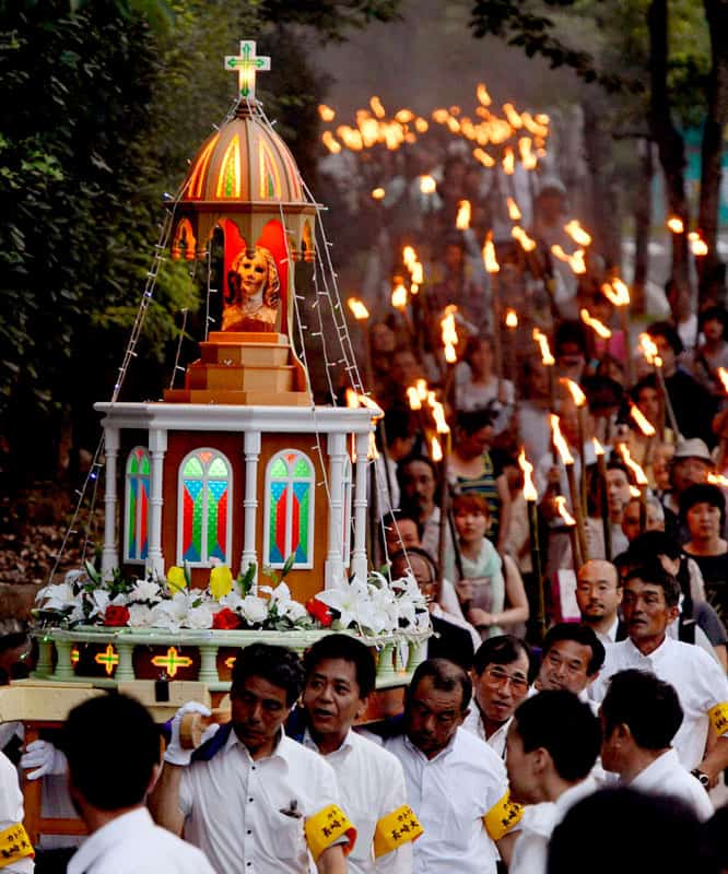 People carry the remains of a statue of Mary that survived the atomic blast over Nagasaki, Japan, as they march through the streets of the city Aug. 9, 2012. (CNS photo/Kyodo, Reuters)