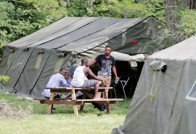 asylum changes: Refugees in Lacolle, Canada, sit outside one of the tents set up to house the influx of asylum- seekers near the U.S. border Aug. 10, 2017. (CNS photo/Christinne Muschi, Reuters)