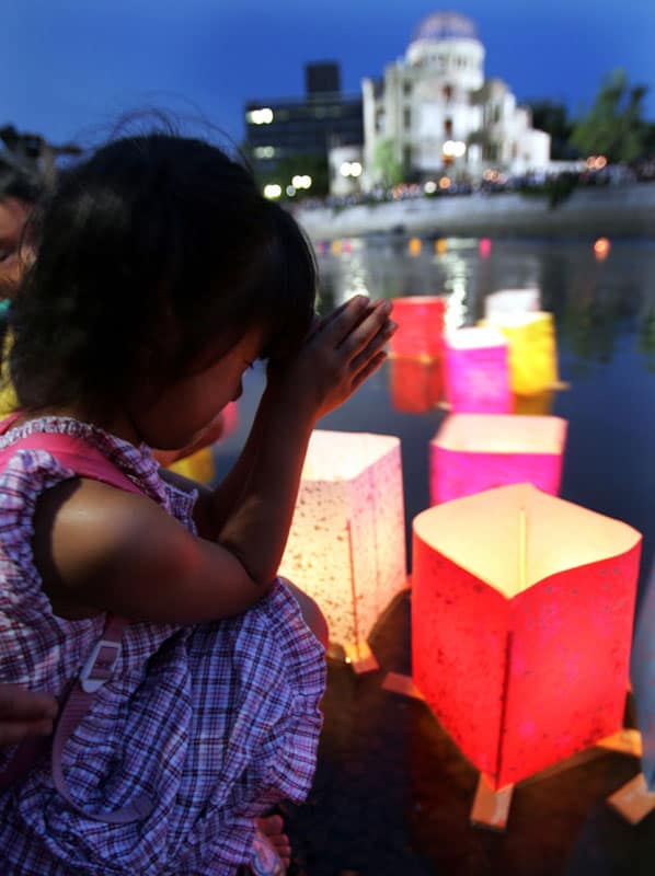 A girl prays after releasing a paper lantern on the Motoyasu River facing the gutted Atomic Bomb Dome in Hiroshima, Japan, Aug 6, 2020, the 75th anniversary of the U.S. dropping the atomic bomb on Hiroshima. (CNS photo/Yuriko Nakao, Reuters)