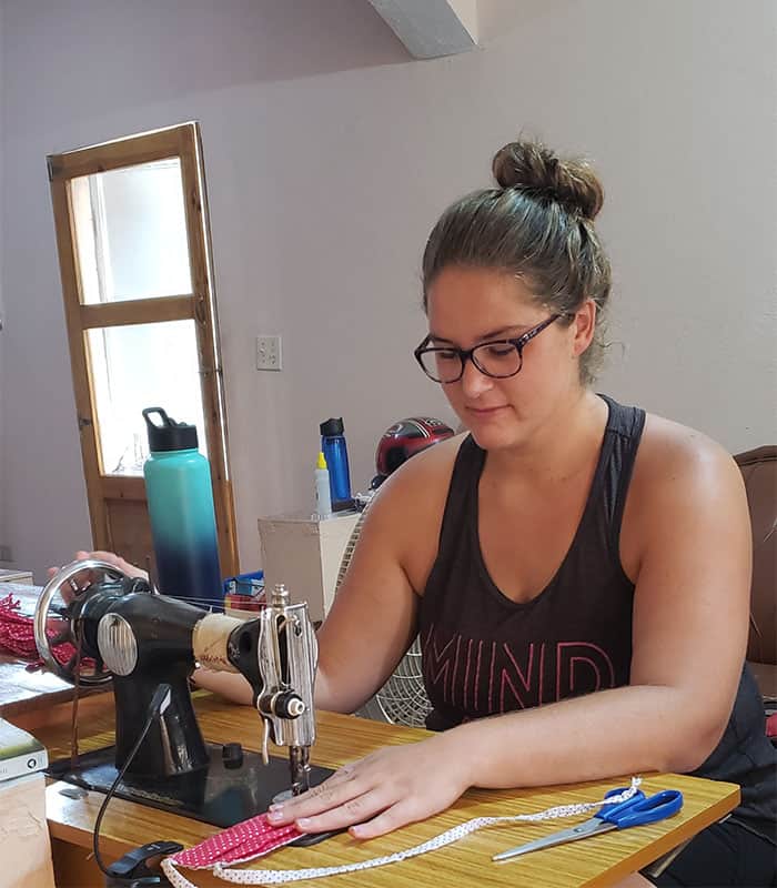 Abby Belt, a Maryknoll lay missioner from Wichita, Kansas, uses an old treadle sewing machine to make masks for her neighbors in Haiti during COVID-19 pandemic. (Courtesy of Abby Belt/Haiti),