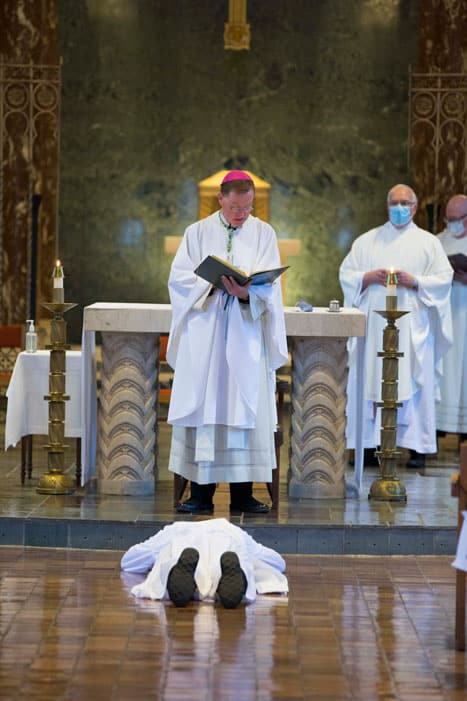 McPhee lies prostrated on the ground while Bishop Edmund J. Whalen recites the Litany of Supplication. (Octavio Duran/U.S.)