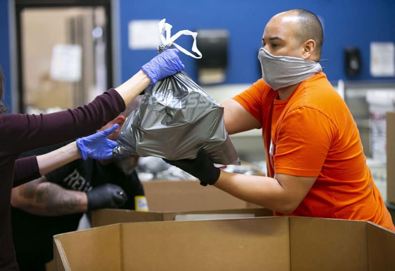 Adam Cadena, a United Food Bank volunteer, takes emergency food bags and places them in boxes at the United Food Bank warehouse in Mesa, Arizona, in this April 16, 2020, file photo. In an interview, Cardinal Pietro Parolin, Vatican secretary of state, said putting a priority on the human person is needed for economic recovery from the coronavirus pandemic. (CNS photo/David Wallace, Reuters)