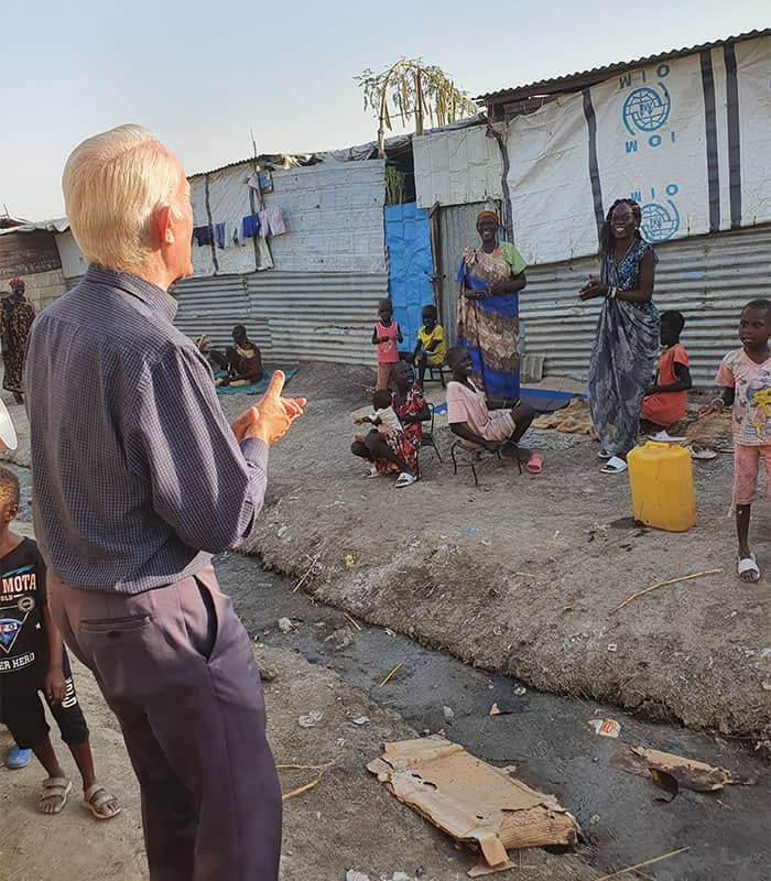 Outside their houses, mothers and children in U.N. camp for displaced persons greet their chaplain, Maryknoll Father Michael Bassano. (Courtesy of Michael Bassano/South Sudan)