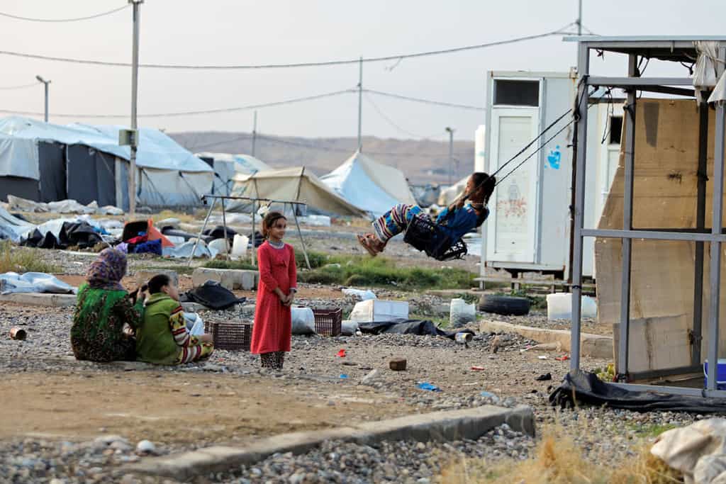 A girl near Mosul, Iraq, plays on a makeshift swing at Hammam Al-Alil camp where displaced Iraqis prepare to be evacuated Nov. 10, 2020. With asylum-seekers Biden story. (CNS/Abdullah Rashid, Reuters)