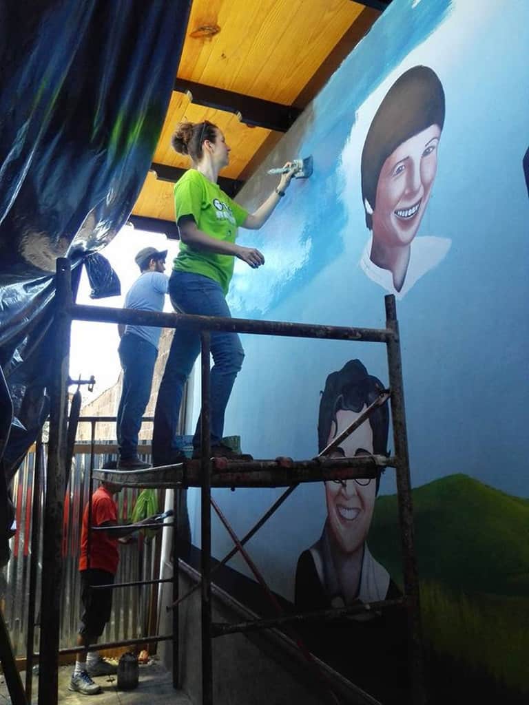 Melissa Altman of the Maryknoll Lay Missioners paints the sky in a mural Dec. 11, 2016, in Zaragoza, El Salvador, featuring the four U.S. Catholic women assassinated in the Central American country Dec. 2, 1980. Four decades after the killings, Altman, who serves in mission with her family in El Salvador, said the women's example of faith continues to inspire her to continue their work. (CNS/Fatima Pacas for International Partners in Mission via of Melissa Altman of Maryknoll Lay Missioners)