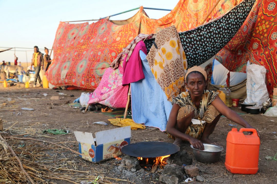 An Ethiopian who fled the ongoing fighting in Tigray region prepares a meal before being processed for emergency food and logistics support by the World Food Program at a camp in Kassala, Sudan, Nov. 17, 2020. (CNS/World Food Program handout via Reuters)