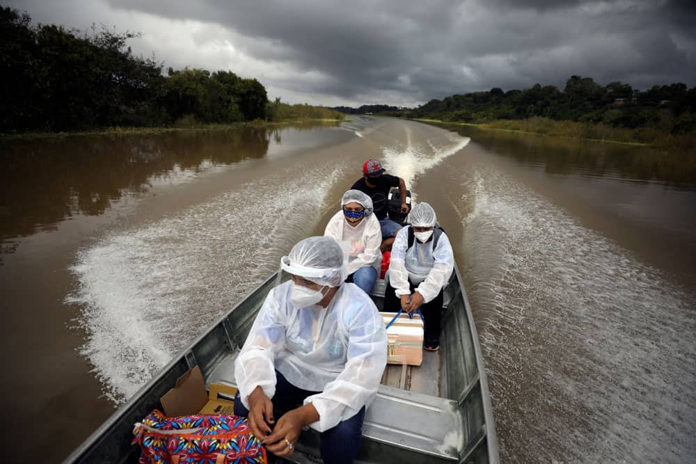 Municipal health workers travel on a boat along the Solimoes River to apply the Oxford-AstraZeneca vaccine for COVID-19 to the residents who live along the river in Manacapuru, Amazonas state, Brazil, Feb. 1, 2021. (CNS photo/Bruno Kelly, Reuters)