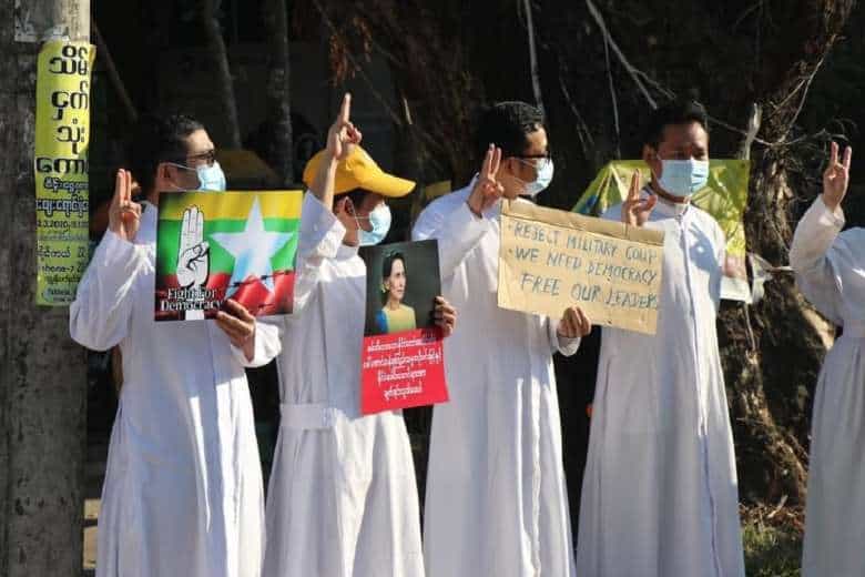Catholic priests hold a picture of State Counselor Aung San Suu Kyi while others display the three-finger salute during an anti-coup protest in Pathein, Irrawaddy division, on Feb. 10, 2021. (Photo: OSC Pathein)
