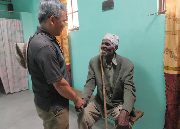 Father Dinh greets a local man at the medical clinic he helps support in Ndoleleji parish.