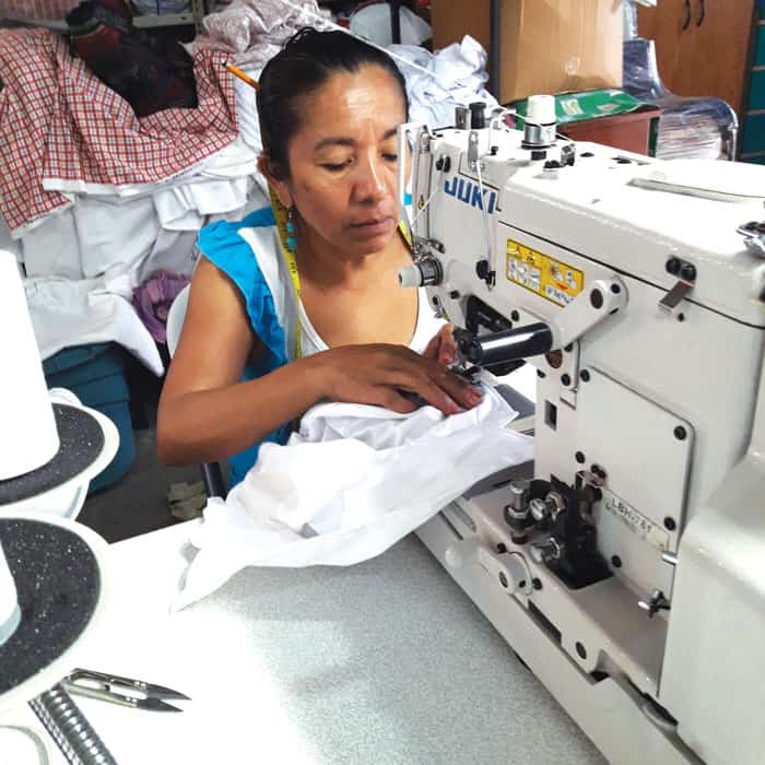 Esmeralda sews buttons on school uniform shirts at Acomujerza cooperative, where she has worked for 15 years and is now a head seamstress. (Ana Morales/El Salvador)