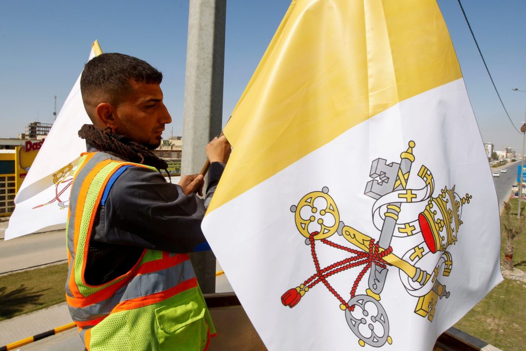 A worker hangs the Vatican flag on a utility pole in Najaf, Iraq, Feb. 27, 2021. Pope Francis plans to visit Iraq March 5-8. (CNS photo/Alaa Al-Marjani, Reuters)