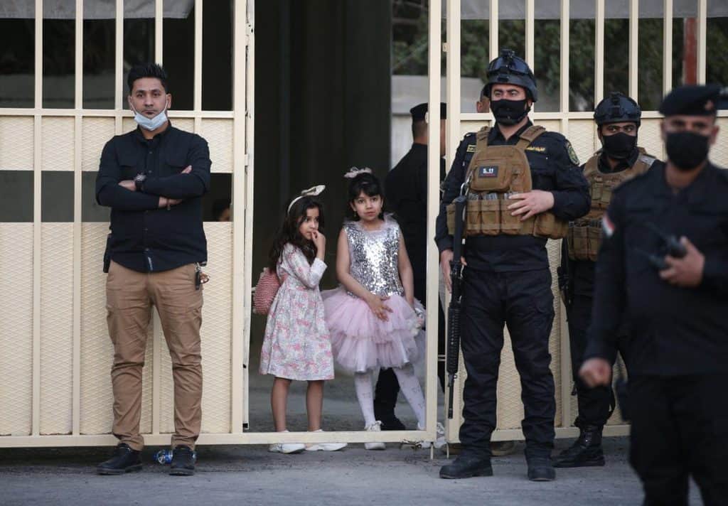 Young girls watch near security personnel after Pope Francis' meeting with bishops, priests, religious men and women, seminarians and catechists in the Syriac Catholic Cathedral of Our Lady of Deliverance in Baghdad, Iraq, March 5, 2021. (CNS photo/Paul Haring)