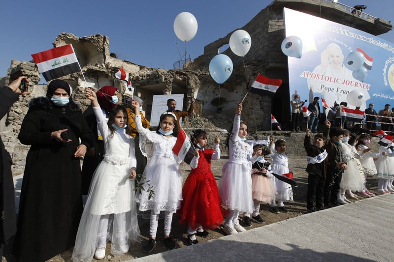 Children wave Iraqi flags before Pope Francis' arrival for a memorial prayer for the victims of the war at Hosh al-Bieaa (church square) in Mosul, Iraq, March 7, 2021. (CNS photo/Paul Haring)