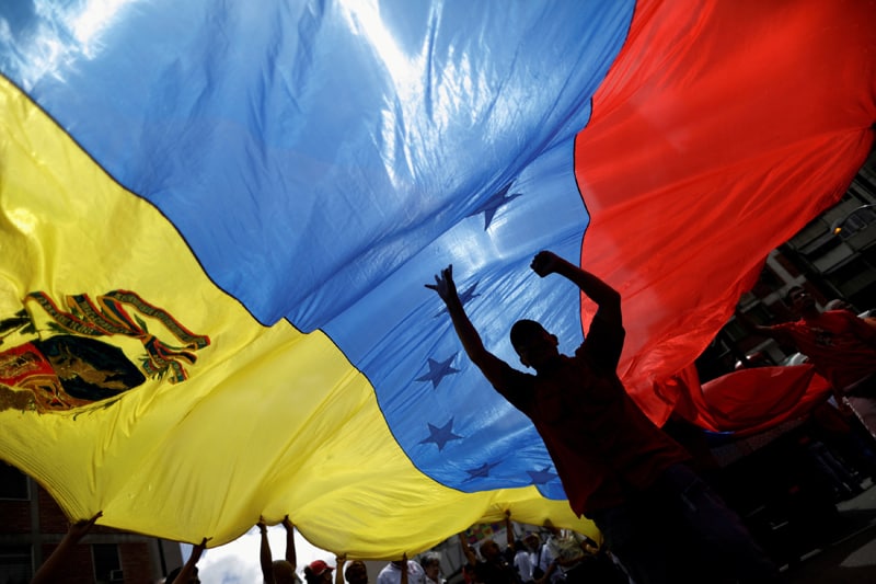 VENEZUELA RALLY Supporters of President Nicolas Maduro hold a Venezuela flag during a rally in Caracas Aug. 14, 2017. The Biden administration announced March 8, 2021, it is offering 18-months of Temporary Protected Status to about 320,000 Venezuelans in the U.S. who fled their country's economic collapse. (CNS photo/Ueslei Marcelino, Reuters)
