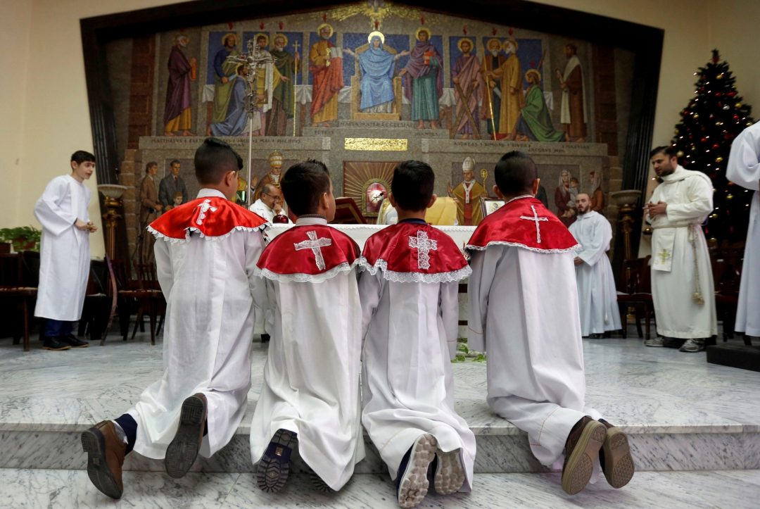 Displaced Iraqi Christian boys, whose families fled religious persecution, serve Mass Dec. 24, 2017, at a Catholic church in Amman, Jordan. (CNS photo/Muhammad Hamed, Reuters)