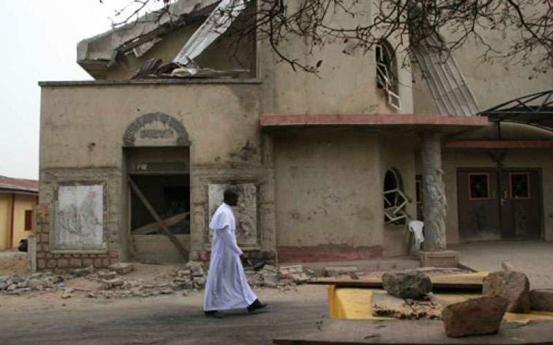 A Catholic Priest walks in front of damaged St. Leo the Great Catholic Church in Enugu State, Nigeria. Credit: Aid to the Church in Need (ACN)