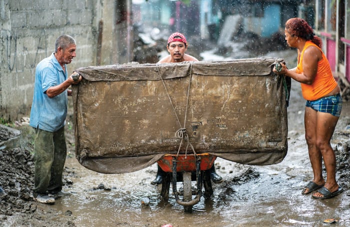 Residents move a reclaimed couch during a torrential rainstorm in Chamelecón, a neighborhood of San Pedro Sula, Honduras. They hope to clean and resell it to those who lost everything during Hurricanes Eta and Iota last year. (Gregg Brekke/Honduras)