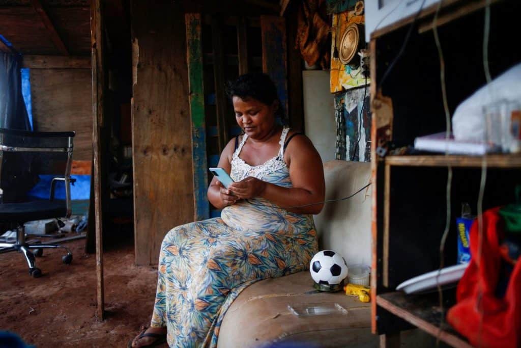 WOMAN SQUATTED LAND BRAZIL Tatiana Araujo de Sirqueira, 33, uses a cell phone in her home set up on land near Planalto Palace during the coronavirus pandemic in Brasília, Brazil, March 3, 2021. In a message to participants of the World Bank Group and International Monetary Fund 2021 virtual spring meetings, Pope Francis called for debt relief and said poor countries cannot be expected to recover from the current financial crisis if the world returns to an economic model in which a small minority of people owns half of the world's wealth. (CNS photo/Adriano Machado, Reuters)