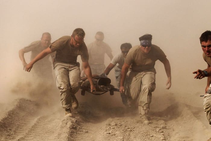 Members of the Navy in Kandahar province in southern Afghanistan carry a comrade wounded by an explosion to a medevac helicopter Oct. 2, 2010. (CNS photo/Finbarr O'Reilly, Reuters)