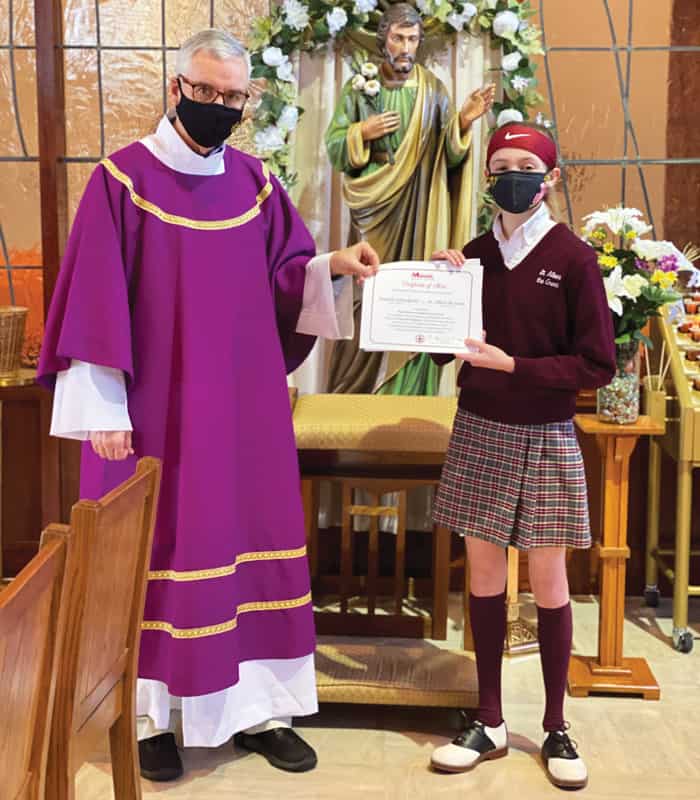 Deacon Kevin McCarthy gives Danielle Carradorini, a seventh-grader at Saint Albert the Great School in Huntington Valley, Pennsylvania, the first-place Bishop Francis X. Ford Award for Division I of the Maryknoll Student Essay Contest.