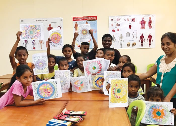 Sister Wanzagi beams in the background as children she mentors show off their artwork. (Courtesy of Susan Wanzagi/East Timor)