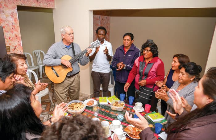 Father Masson, playing the guitar, and Maryknoll Seminarian John Siyumbu (white shirt) meet with Christian communities at Father Masson’s home. (Nile Sprague/Bolivia)