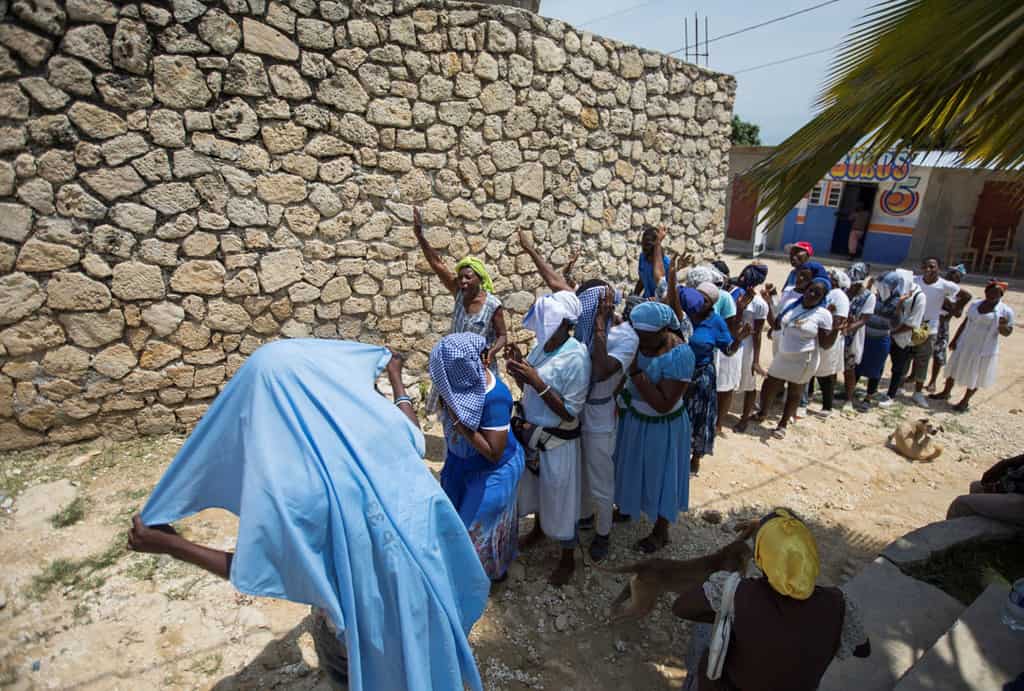 People pray near the Church of St. Roch in Port-au-Prince, Haiti, April 12, 2021. A French priest, two nuns and three laypeople who were abducted together on their way to the parish April 11. (CNS photo/Valerie Baeriswyl, Reuters)