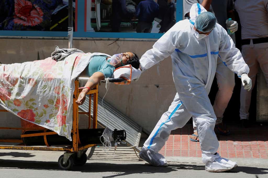 Web-INDIA-COVID-CHURCH-1246604 A health care worker wearing personal protective equipment pulls a patient suffering from COVID-19 on a stretcher outside Guru Teg Bahadur hospital in New Delhi April 24, 2021. (CNS photo/Adnan Abidi, Reuters)