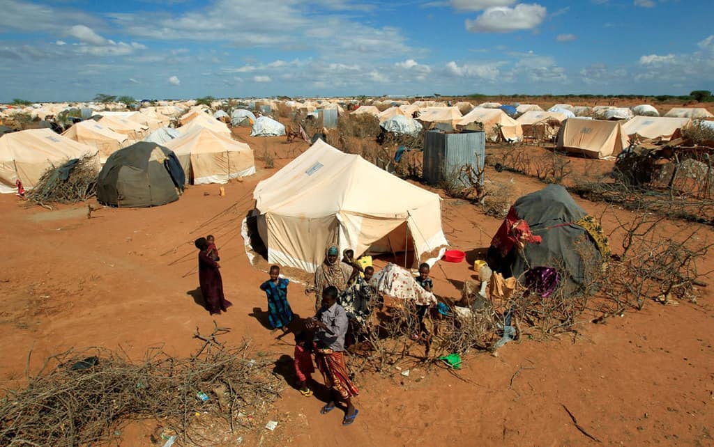 Refugees stand outside their tent in 2011 at a refugee camp in Dadaab, Kenya, across the border from Somalia. Catholic bishops in Kenya are urging the government to shelve plans to close Dadaab and Kakuma refugee camps that host refugees who fled civil war and famine in Somalia and South Sudan. (CNS photo/Thomas Mukoya, Reuters)