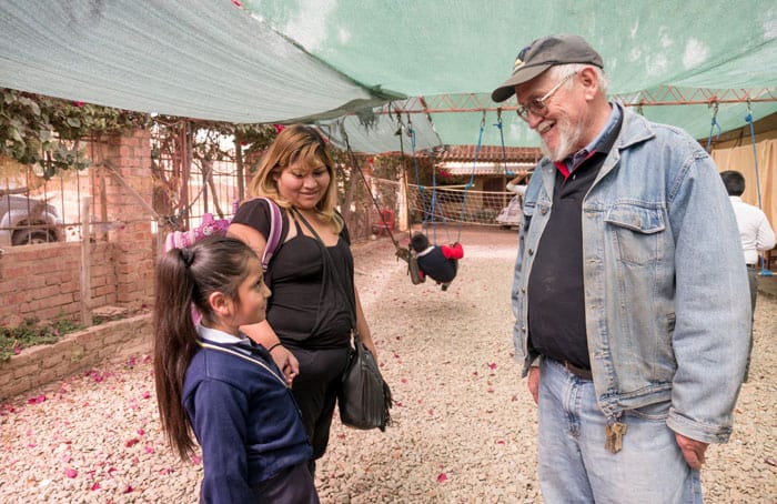 Web-Only-Sim-01 Before COVID-19, Father Paul Sykora welcomes a mother and daughter to the after-school tutoring center in Nueva Vera Cruz, Cochabamba, Bolivia. (Nile Sprague/Bolivia)