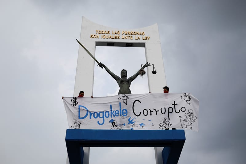 People hold a banner next to a monument in San Salvador, El Salvador, May 2, 2021, as they protest the Salvadoran congress' removal of constitutional court judges and the attorney general. (CNS photo/Jose Cabezas, Reuters)