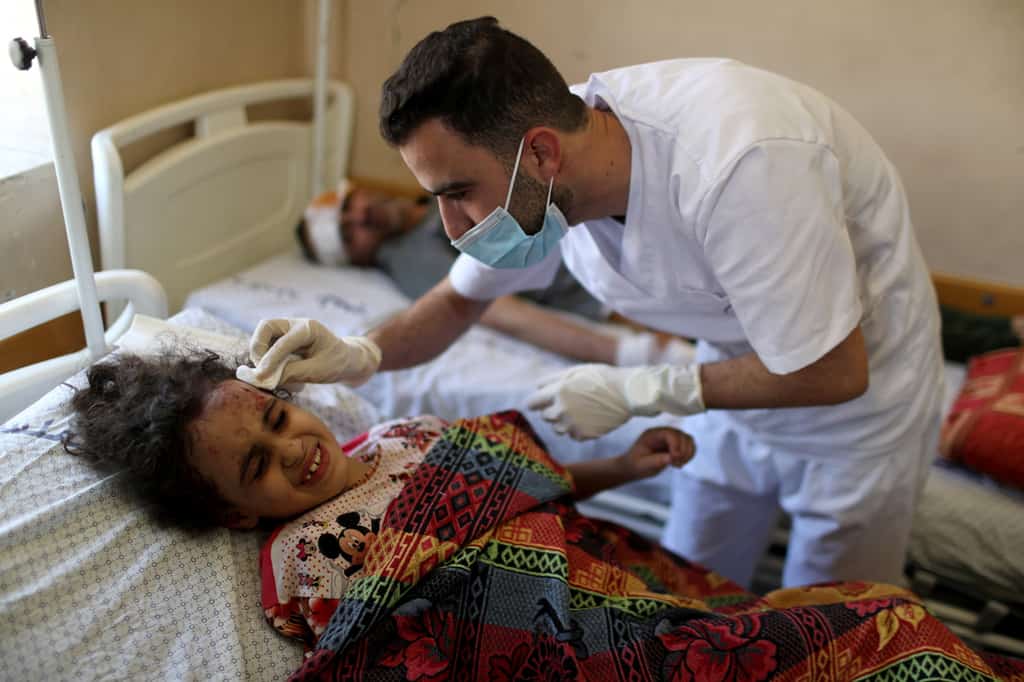 Palestinian Suzy Eshkuntana, 6, is treated by a medic at a hospital after being pulled from the rubble of a building during Israeli airstrikes in Gaza City May 16, 2021. (CNS photo/Mohammed Salem, Reuters)