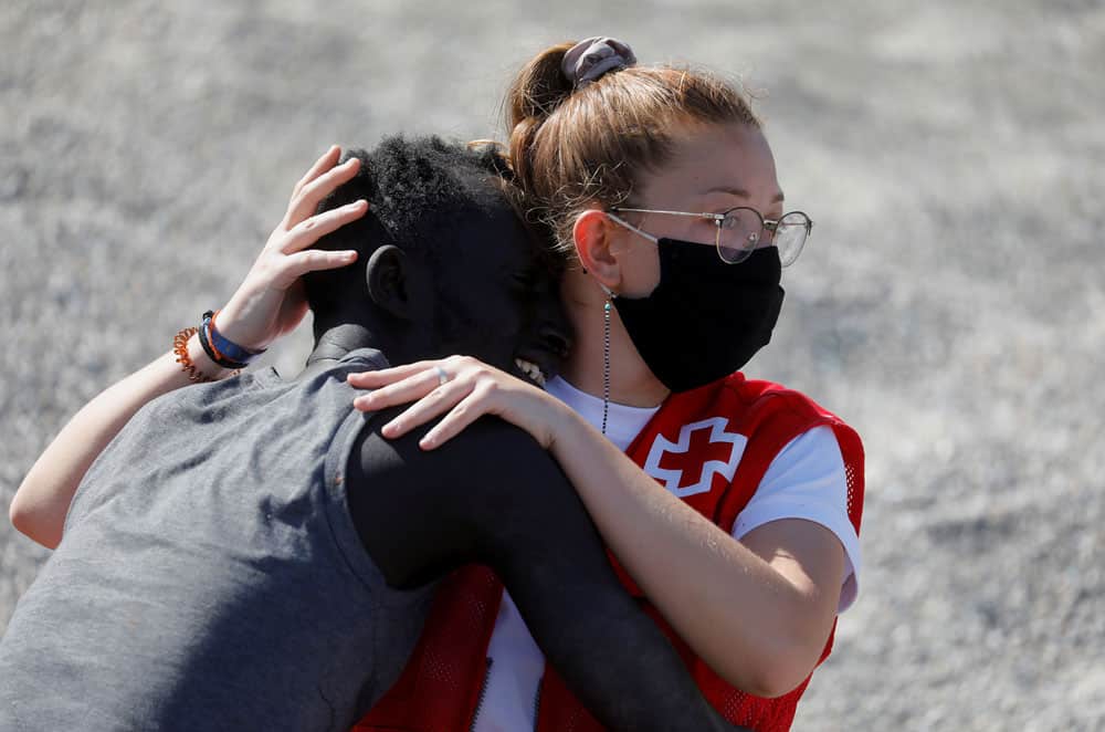 A member of the Red Cross helps a Moroccan citizen at El Tarajal beach, near the fence between the Spanish-Moroccan border, after thousands of migrants swam across this border in recent days, in Ceuta, Spain, May 18, 2021. In a statement released May 18, the Spanish bishops' conference expressed concern that migrants were being exploited after a sudden of influx of refugees into the Spanish territories of Ceuta and Melilla increased tensions between Spain and Morocco. (CNS photo/Jon Nazca, Reuters)