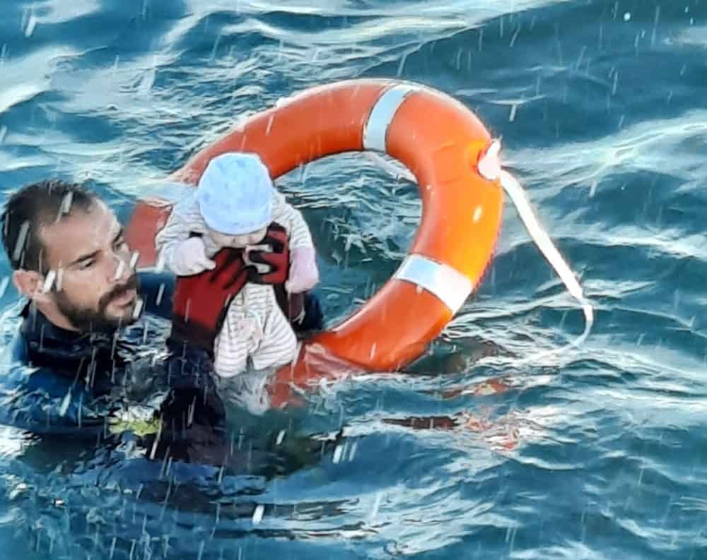 A member of the Spanish Civil Guard holds a migrant baby in the water off the shore of the Spanish enclave of Ceuta in this handout picture released by the Civil Guard May 18, 2021. In a statement released May 18, the Spanish bishops' conference expressed concern that migrants were being exploited after a sudden of influx of refugees into the Spanish territories of Ceuta and Melilla increased tensions between Spain and Morocco. (CNS photo/Spanish Civil Guard via Reuters)