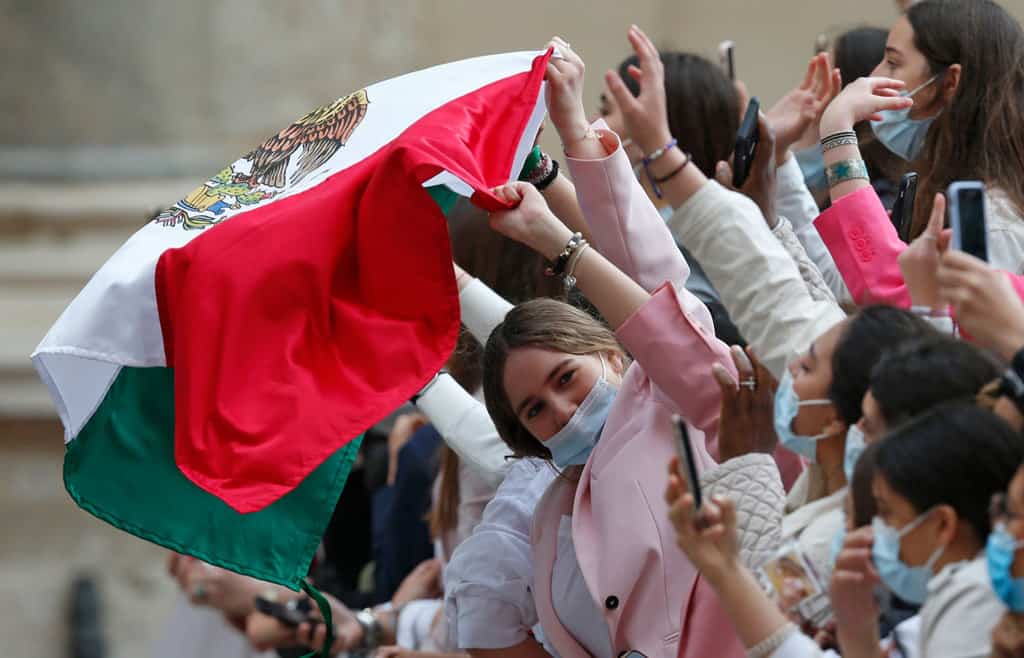 A young woman waves the Mexican flag as Pope Francis leads his general audience about perseverance in prayer in the San Damaso Courtyard of the Apostolic Palace at the Vatican May 19, 2021. (CNS photo/Paul Haring)