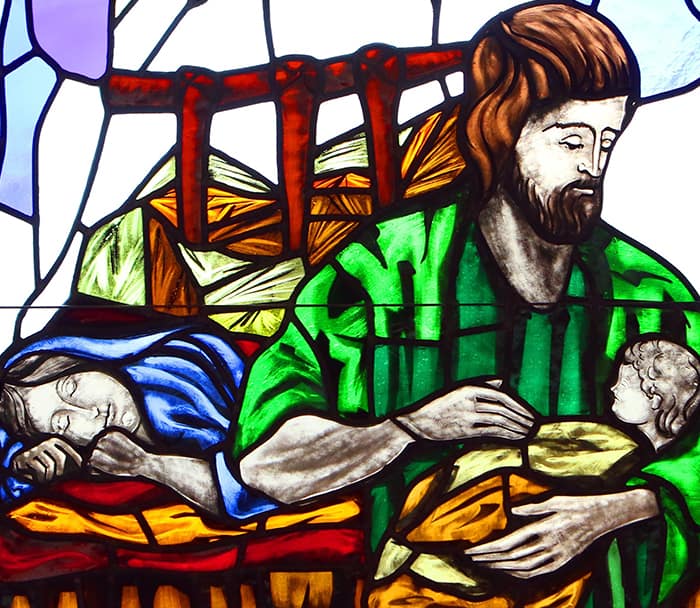 ST. JOSEPH AND CHRIST CHILD For Fathers, St. Joseph Is Strong Model of Humility, Service, Says Priest: A depiction of St. Joseph cradling the infant Jesus while Mary sleeps is seen in a stained-glass window at St. Patrick Church in Smithtown, N.Y. (CNS photo/Gregory A. Shemitz)