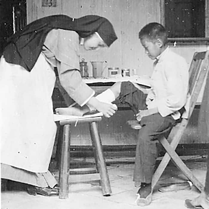 Sister Marie de Lourdes Bourguignon, a registered nurse, treats a young patient in Yeungkong in 1923. (Maryknoll Mission Archives)