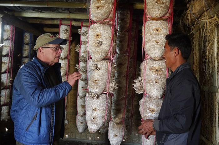 To Feed the World, Start with Family Farms, small farmers Pope Says-farming hunger: Maryknoll Father Joseph Thaler (left) talks to cultivator Chinn Dorje Lama in Thimbu, Nepal, where oyster mushrooms are farmed to sustain families in the area. (Sean Sprague/Nepal)