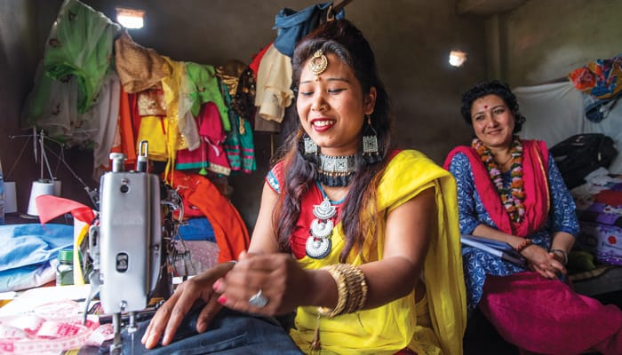 Samjhana Tharu, a graduate of the Sewing Cutting Training Program for Deprived Women in the Bardiya District of Nepal, sews as Shailee Singh Rahour, project director for the Maryknoll Fathers and Brothers in Nepal, proudly looks on. (Gregg Brekke/Nepal)