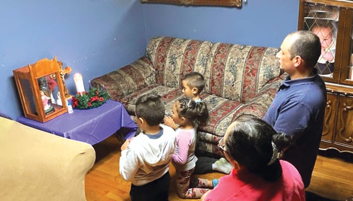 Yngrid and Francisco Flores pray with their children in front of the visiting image of the Holy Family during the 2020 Advent season. (Courtesy of Alejandro Lopez-Cardinale/U.S.)