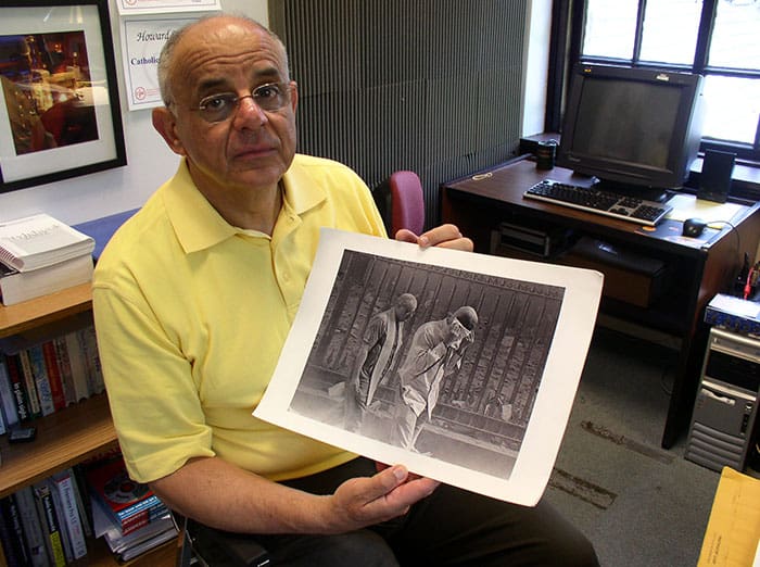 In this file image, Maryknoll Father Raymond Nobiletti holds a photo taken by Gulnara Samoilova on Sept. 11, 2001, after the south tower of the WTC collapsed, covering the priest, who was ministering to burn victims, and everyone nearby in a dark cloud of ashes. (Schwartz/U.S.)