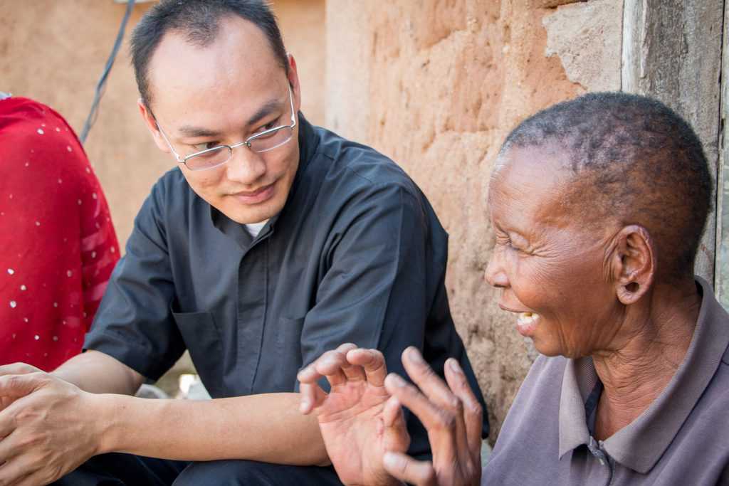 Father Lam Hua (center) talking to Victoria Maltini (right), Mabatini, Mwanza, Tanzania. Photo © Nile Sprague