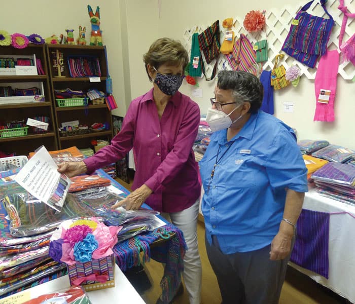 At the cooperative store in El Paso, Gloria Yanez (pink blouse) shows Sister Margaret Sierra handcrafts made by women of the Santa Catalina Center in Ciudad Juarez.