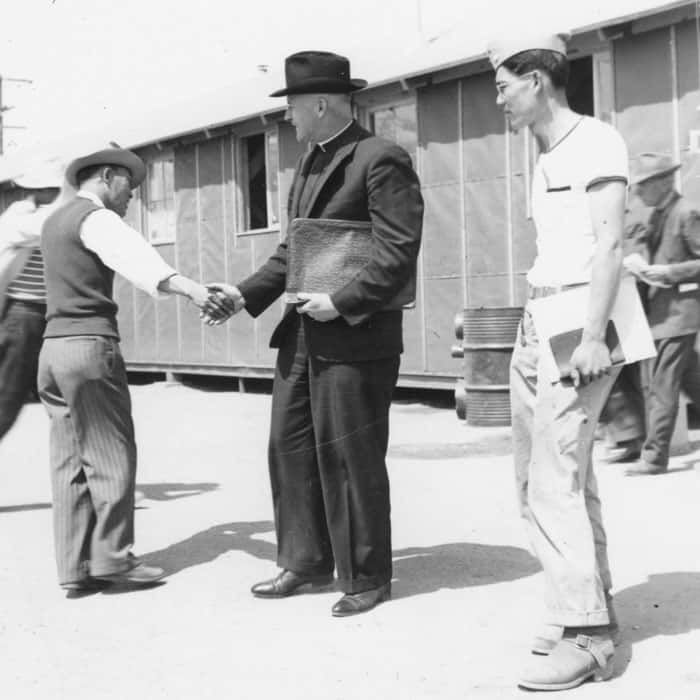 Father Hugh Lavery shakes hands with an internee in Manzanar relocation camp. (Maryknoll Mission Archives)