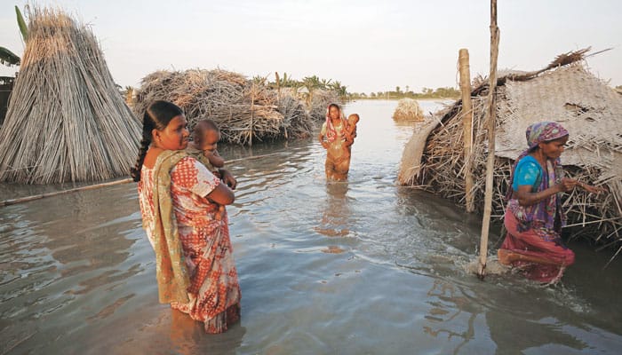 Women carrying babies make their way through an affected area in Bogra, Bangladesh, where floods have worsened in recent years. (CNS/Mohammad Ponir Hossain, Reuters)