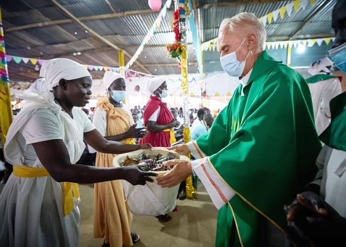Father Bassano receives the offering as he celebrates Mass in a makeshift chapel of scrap lumber and corrugated tin, bringing Shilluk, Nuer and Dinka residents together. (Paul Jeffrey/South Sudan)