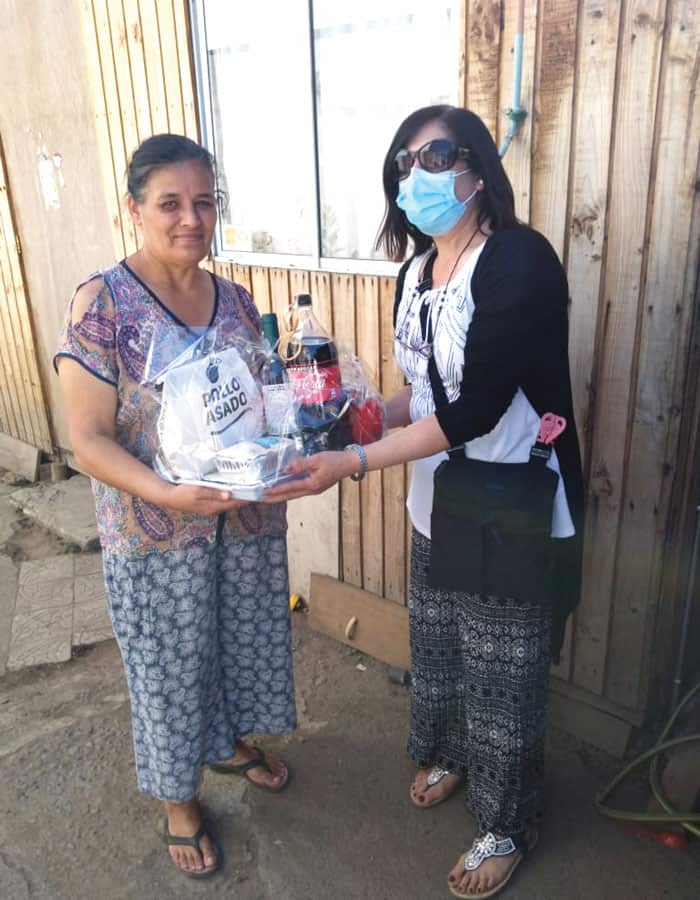 A parishioner of Cristo Resucitado (right) delivers a Christmas dinner donated by the parish in an impoverished neighborhood of Curicó. (Courtesy of Beatriz Abrigo/Chile)