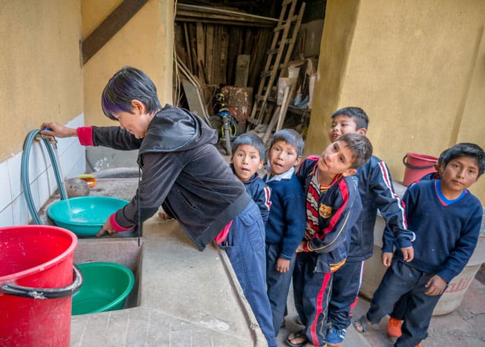 Before the students enjoy a snack of oatmeal and milk, Nguyen encourages them to wash their hands at the parish house in Tacopaya, Bolivia. (Nile Sprague/Bolivia)