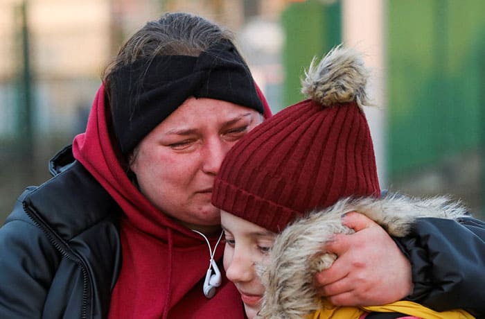 A woman becomes emotional as she embraces a youth at a border crossing between Poland and Ukraine in Medyka, Poland, Feb. 26, 2022, after Russia launched a massive military operation against Ukraine. Russian troops stormed toward Ukraine's capital of Kyiv, and street fighting broke out as city officials urged residents to take shelter. (CNS photo/Kacper Pempel, Reuters)